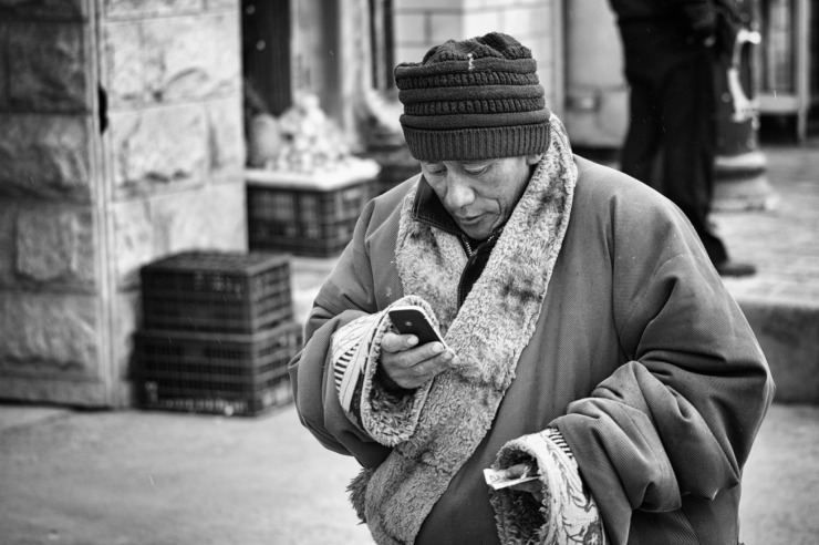 old man in a faraway country looking at a mobile phone