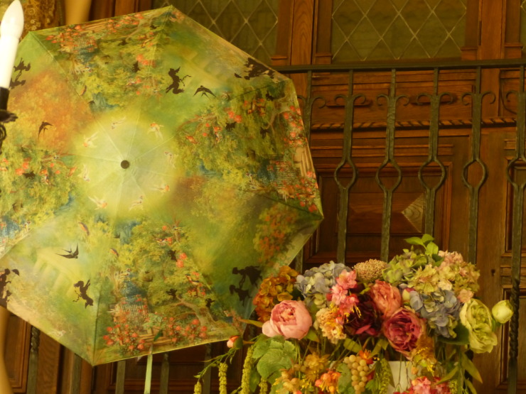a decorated umbrella sits propped up so we can see the top and a bouquet is just to the right 