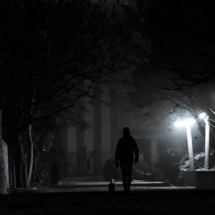 man walks alone on a dark and misty night