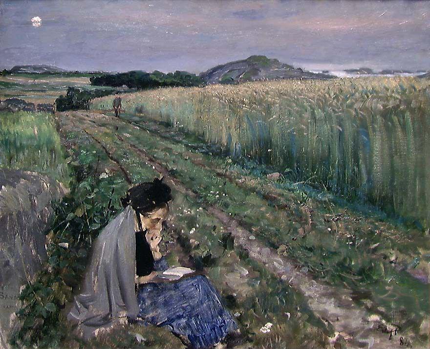 woman reads a book in a field while someone walks up to her 
