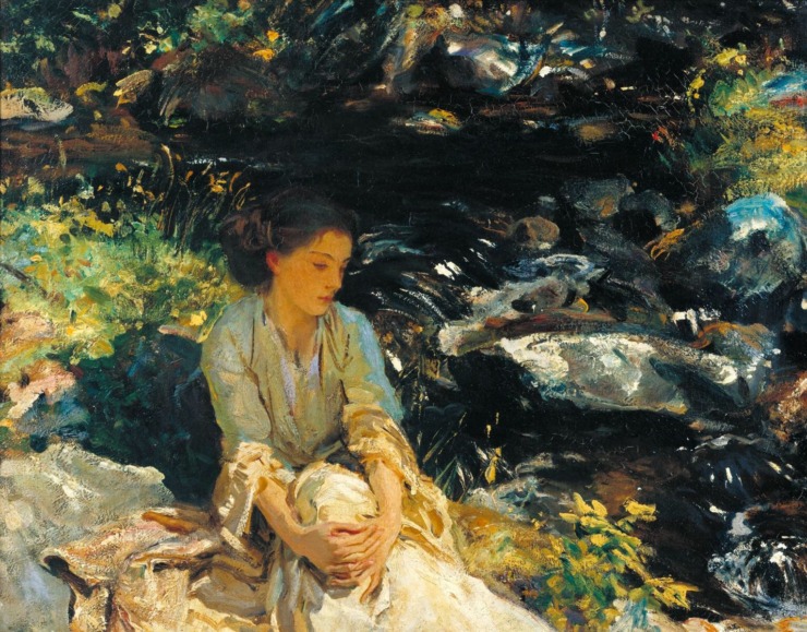 woman sits by a babbling brook 