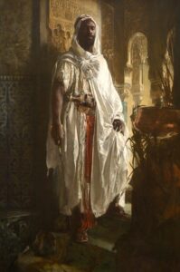 moor chief wearing white robes stands in a doorway